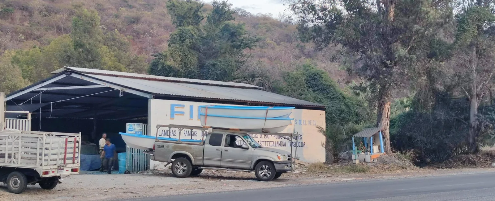 Fachada del punto de venta de FibraTank sobre la carretera, con lanchas de fibra de vidrio